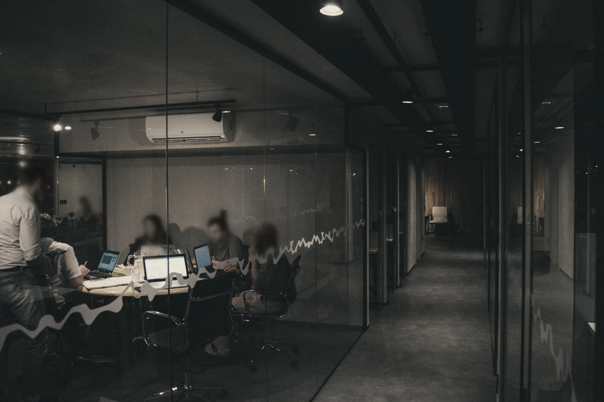 A team meeting in a glass-walled room late in the evening.